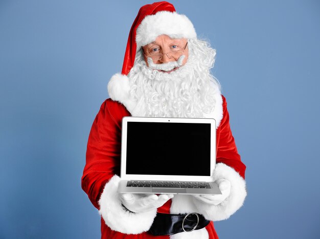 Foto babbo natale tiene in mano un laptop