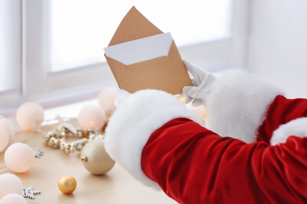 Санта-Клаус держит письмо за столом