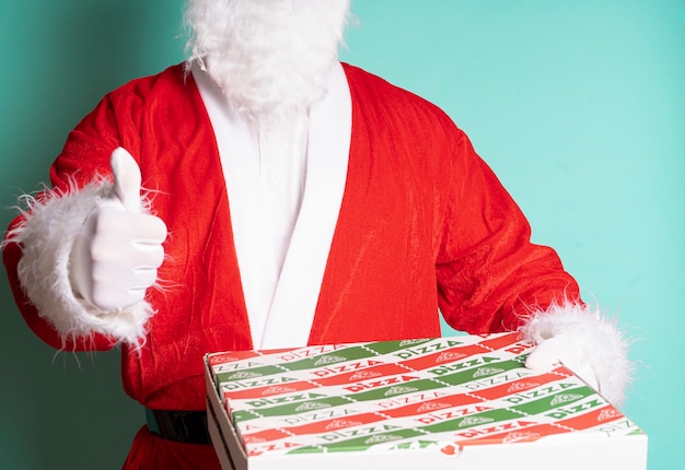 Santa Claus holding a pizza box and making a thumbs up sign isolated on blue