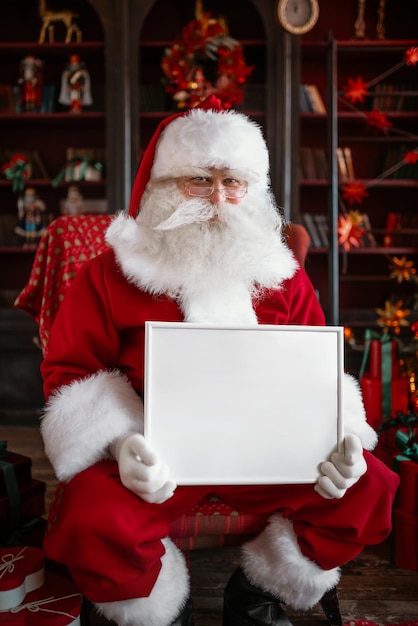 Foto babbo natale con una cornice bianca tra le mani