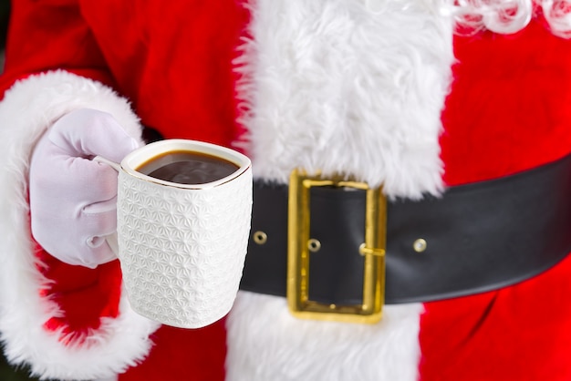 Santa claus holding white mug with coffee in his hand closeup
