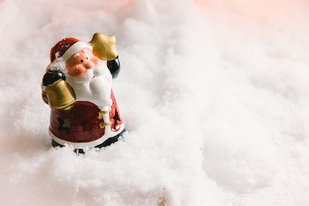 Santa Claus houdt de bel en sterren staan ​​in de sneeuw.