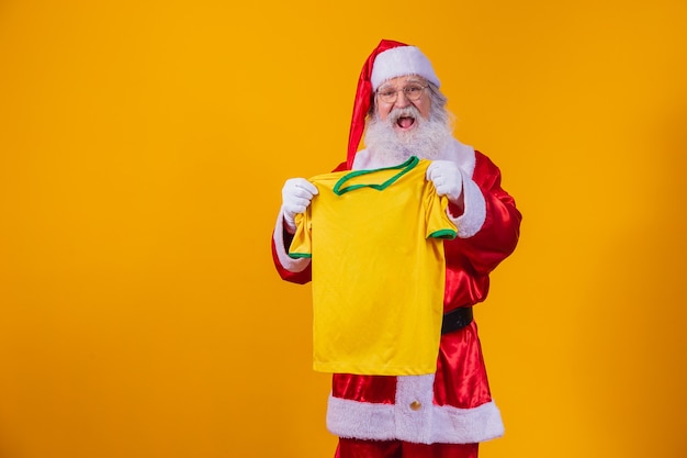 Babbo natale è un fan del brasile. babbo natale tifoso della squadra brasiliana. campionato sportivo. babbo natale che tiene la maglia della squadra. partita di calcio.