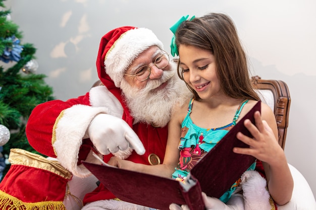 Santa Claus leest een verhalenboek voor een kind op schoot