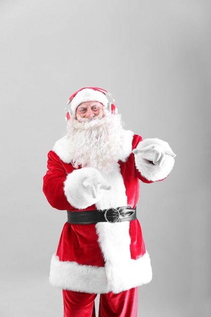 Santa Claus listening to music on light background