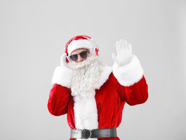 Santa Claus listening to music on light background