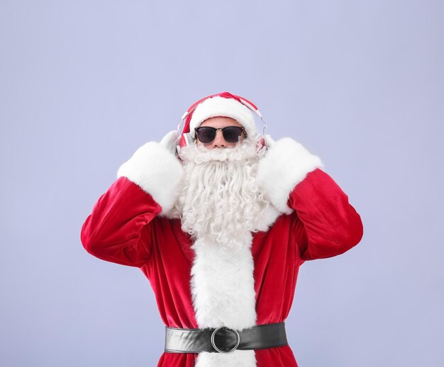 Santa Claus listening to music on light background