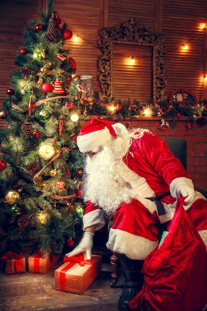 Santa Claus in the living room. Santa Claus puts gifts in a bag