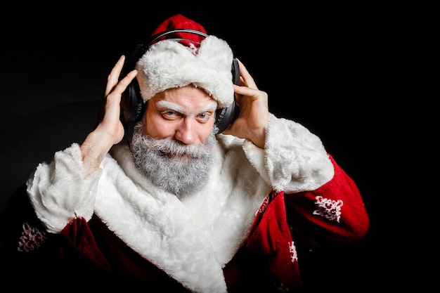 Santa Claus luistert naar muziek met een koptelefoon op een zwarte achtergrond