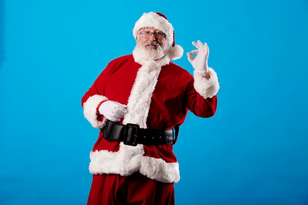 Santa Claus making OK gesture on blue background