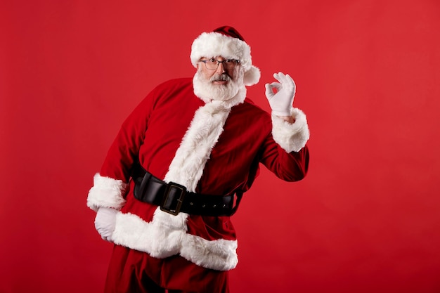 Santa Claus making OK gesture on red background