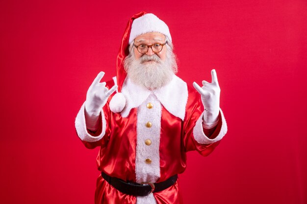 Santa Claus making rock n roll sign with hands and red background.