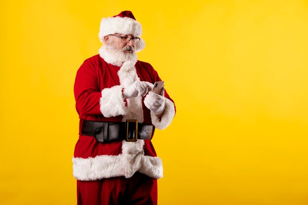 Santa claus met behulp van een mobiele telefoon op gele achtergrond