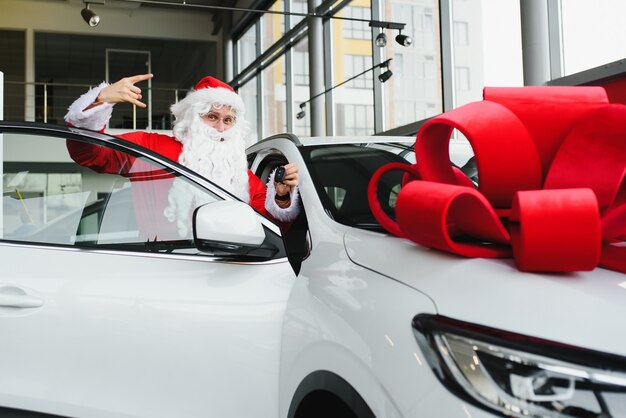 Дед Мороз возле новой машины в автосалоне.