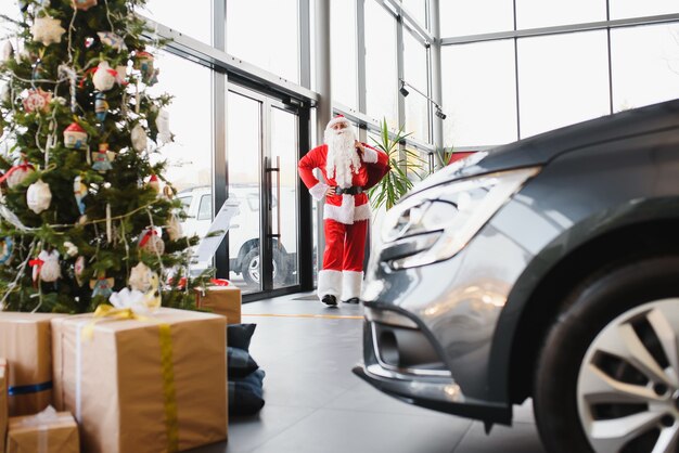 自動車販売店の新車の近くのサンタクロース。