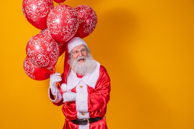 Santa Claus op gele achtergrond met rode ballonnen.