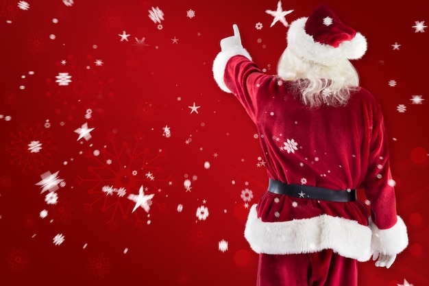 Santa Claus points at something against red snowflake background