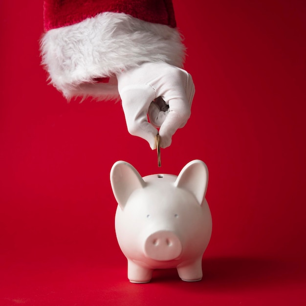 Photo santa claus putting money into a christmas piggy bank money box festive saving concept