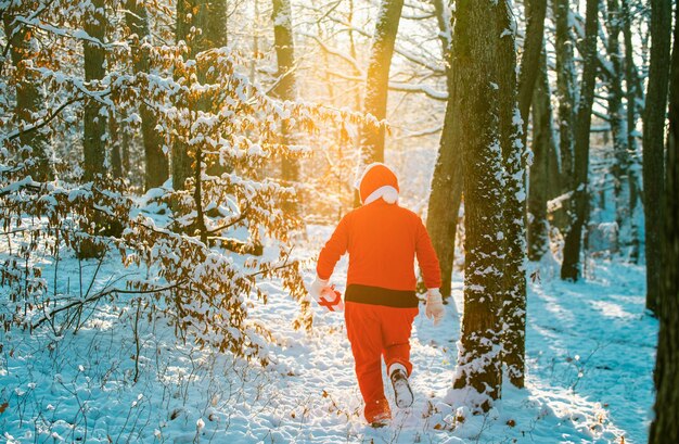 Santa claus in red costume walk in winter forest delivery christmas gifts happy new year merry