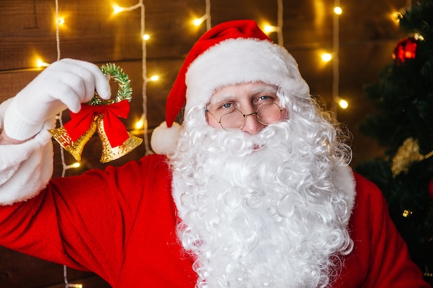 Дед Мороз звонит в колокольчик возле елки с подарками
