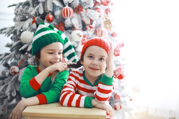 サンタクロースのヘルパー。クリスマスのために美しく装飾された部屋でクリスマスエルフの衣装を着たかわいい子供たち。奇跡の時。サンタクロースからの贈り物。