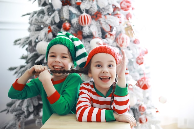 サンタクロースのヘルパー。クリスマスのために美しく装飾された部屋でクリスマスエルフの衣装を着たかわいい子供たち。奇跡の時。サンタクロースからの贈り物。