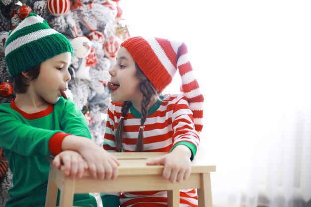 サンタクロースのヘルパー。クリスマスのために美しく装飾された部屋でクリスマスエルフの衣装を着たかわいい子供たち。奇跡の時。サンタクロースからの贈り物。