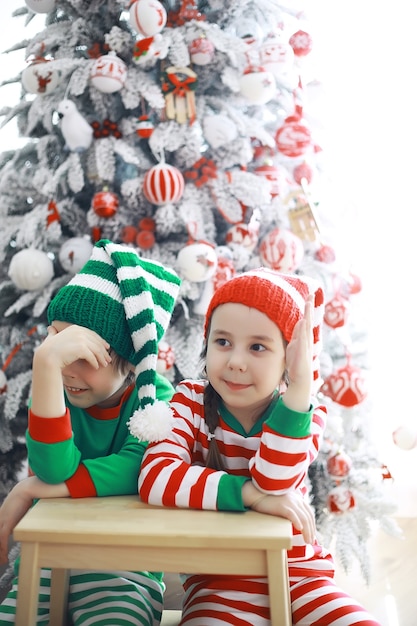 Santa claus's helpers.schattige kinderen in kerst elf kostuums in een kamer prachtig ingericht voor kerstmis. tijd van wonderen. cadeautjes van sinterklaas.