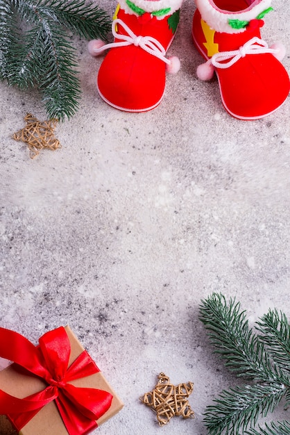 Обувь Санта-Клауса, еловые ветки и подарочная коробка с красными лентами на сером фоне, копией пространства, вид сверху