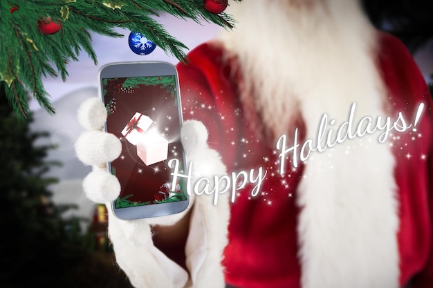 Santa claus showing smartphone against cute village in the snow