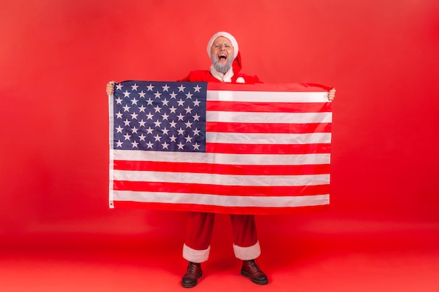 Santa claus showing USA flag and screaming, celebrating enjoying Christmas holidays.