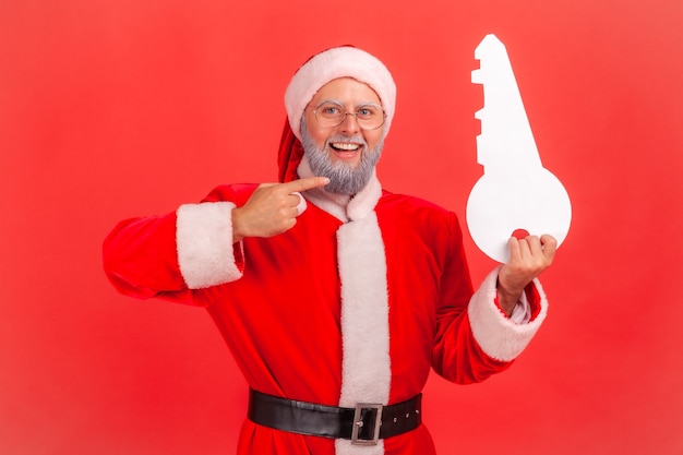 Santa claus standing pointing to paper key, recommend agency for buying apartment.