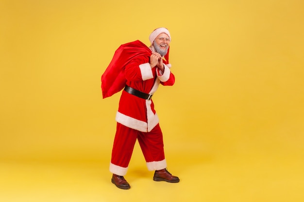 Santa claus standing with big red bag with presents for Christmas holidays.