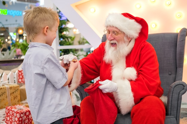 Santa Claus talking and playing surprise games with kids in Shopping Mall. Christmas sales and