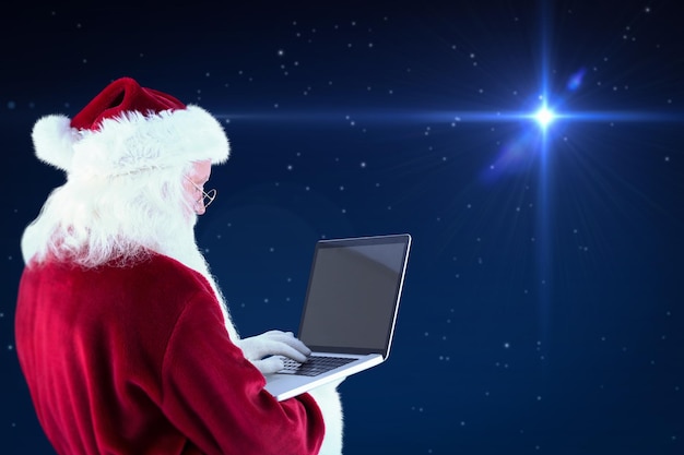 Santa Claus uses a laptop against bright star in night sky