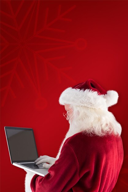 Santa Claus uses a laptop against red background