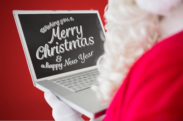 Santa claus using laptop against red background