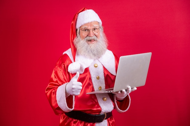 그의 엄지손가락으로 노트북을 사용 하는 산타 클로스