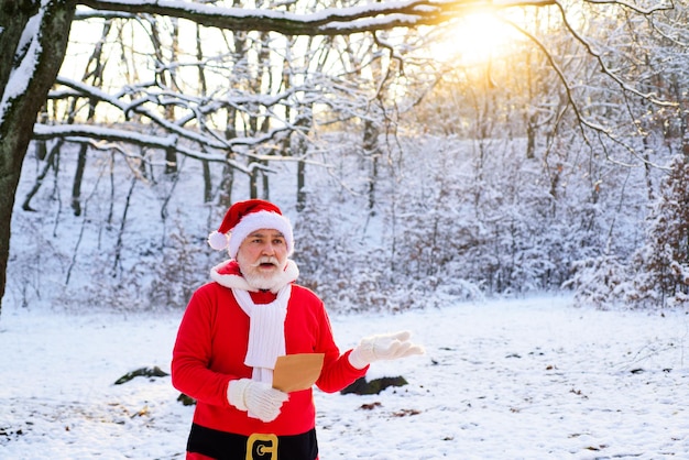 Санта-клаус с рождественским списком желаний в зимнем лесу на снежном пейзаже с новым годом