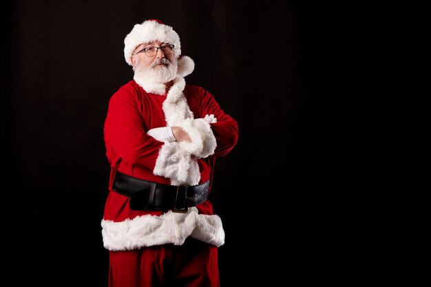 Foto babbo natale con le braccia incrociate su uno sfondo nero