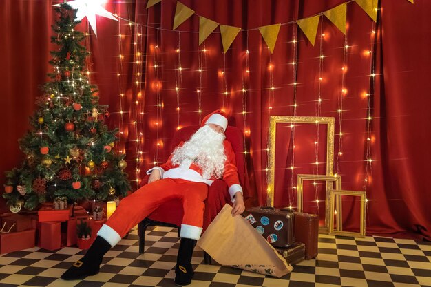 Santa Claus with a gift in his hands on the background of the Christmas tree