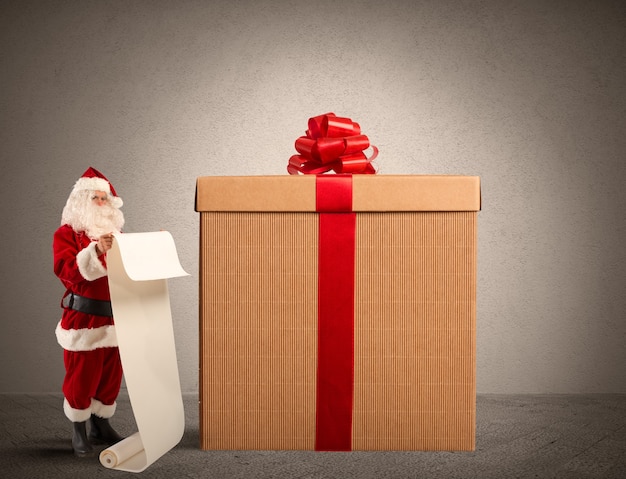 Santa Claus with gifts list and a big present box