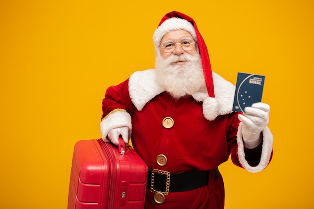 Santa Claus with his suitcase. Holding a brazilian passport. New Year's travel concept