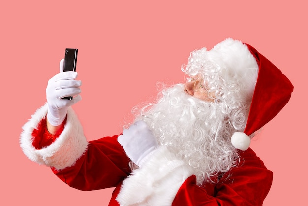 santa claus with mobile phone isolated on pink background