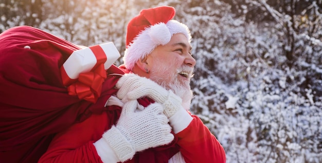 Santa claus with sack full of christmas presents outdoor santa claus walk in the winter snow park