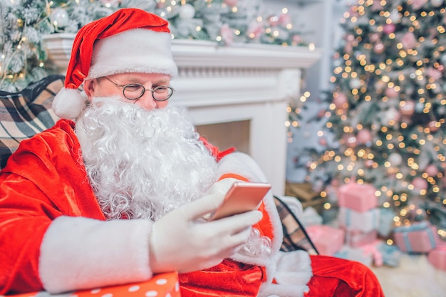 Santa Claus zit en kijkt naar de telefoon