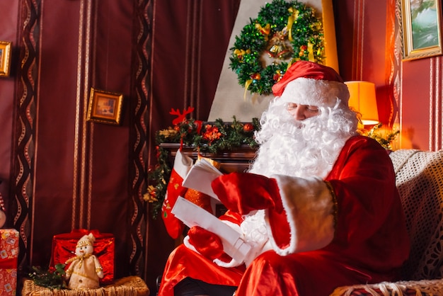 Santa Claus zit naast een kerstboom