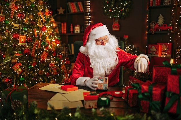 Santa Clause preparing for Christmas packing presents while sitting at the table New Year concept