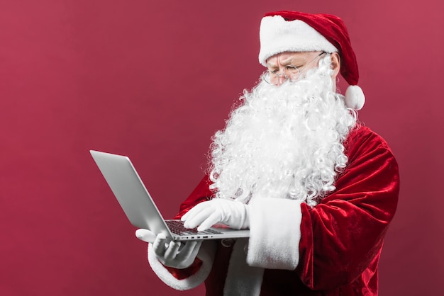 Photo santa in glasses typing on laptop