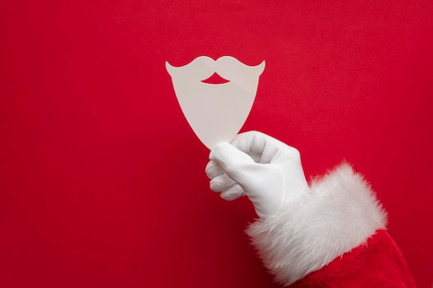 Santa hands holding a white father christmas beard and mustache paper shape